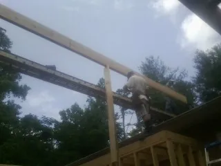 Carpenter setting a ridge beam over a new addition frame — Ice Dam Removal by Roofing Brothers in Barnes City