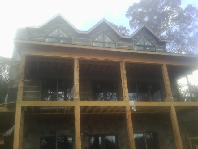 Dormers and porch framing on a large log home under construction — Roof Coating work by our crew in Barnes City