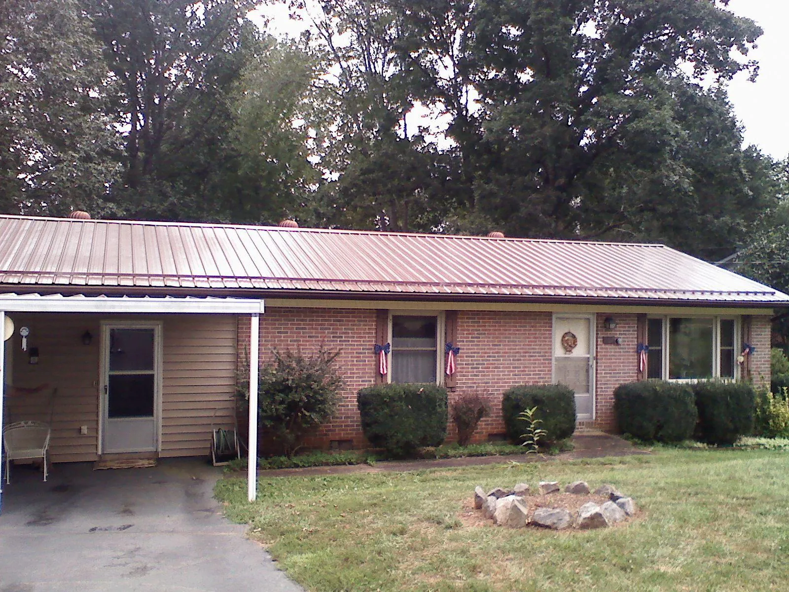 Bronze metal roof and carport on a brick ranch home — Roof Repair work by our crew in Barnes City