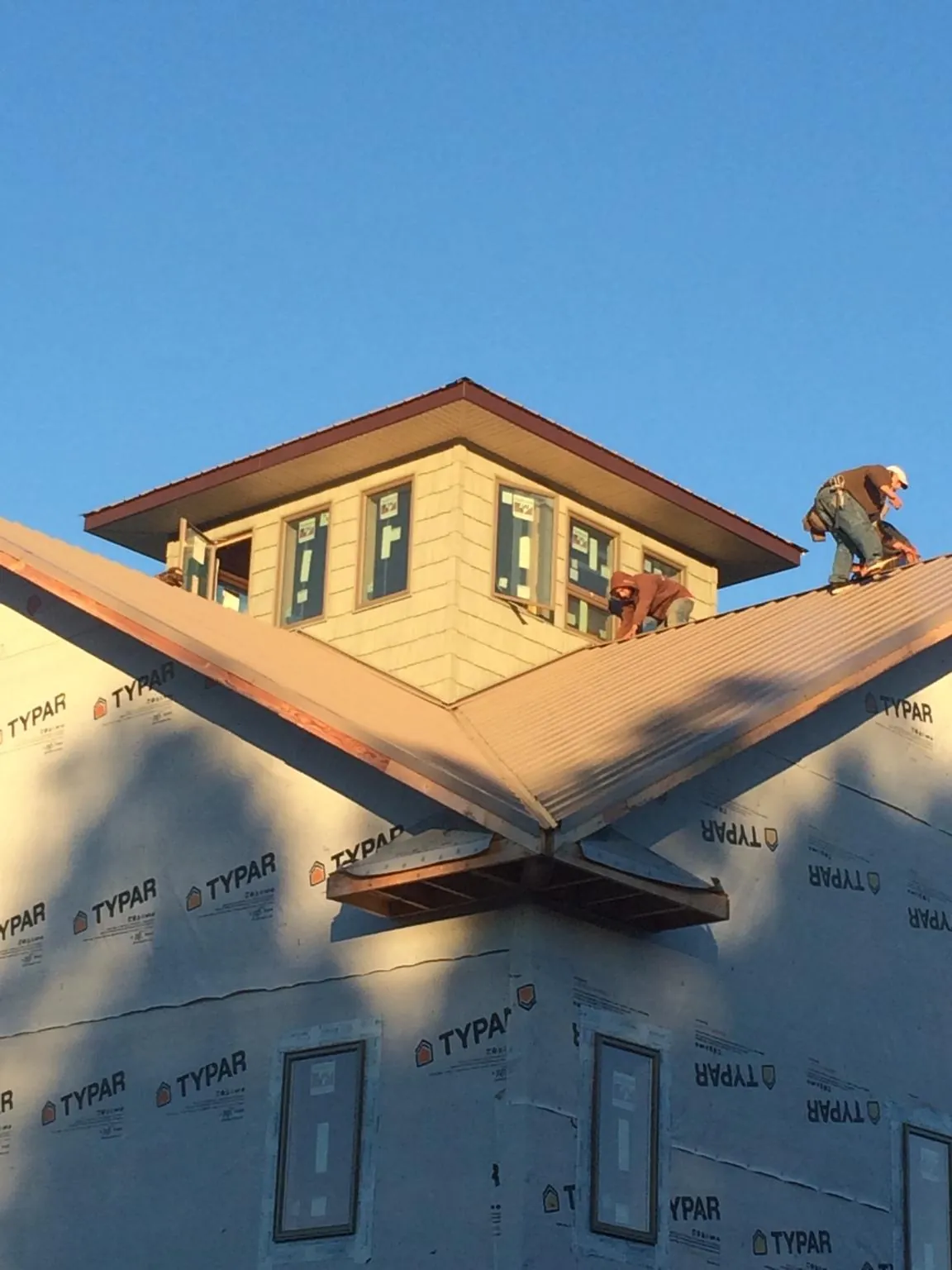 Roofers working around a rooftop cupola on a new metal roof at sunset — Roof Waterproofing in Barnes City by Roofing Brothers